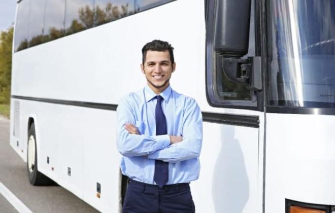 A charter bus driver in front of a bus